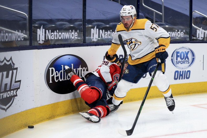 Feb 20, 2021; Columbus, Ohio, USA; Columbus Blue Jackets right wing Oliver Bjorkstrand (28) is checked by Nashville Predators defenseman Dante Fabbro (57) along the boards in the first period at Nationwide Arena. Mandatory Credit: Aaron Doster-USA TODAY Sports