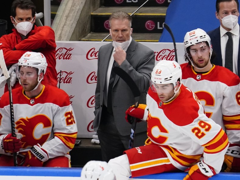 Feb 24, 2021; Toronto, Ontario, CAN; Calgary Flames head coach Geoff Ward (center) on the bench against the Toronto Maple Leafs during the first period at Scotiabank Arena. Mandatory Credit: John E. Sokolowski-USA TODAY Sports