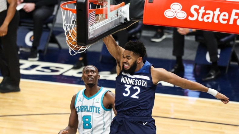 Mar 3, 2021; Minneapolis, Minnesota, USA; Minnesota Timberwolves center Karl-Anthony Towns (32) dunks the ball while Charlotte Hornets center Bismack Biyombo (8) looks on in the first quarter at Target Center. Mandatory Credit: David Berding-USA TODAY Sports