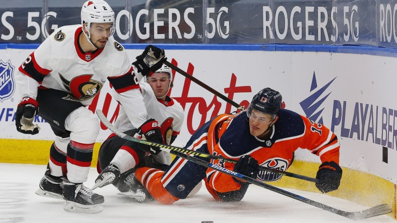 Mar 8, 2021; Edmonton, Alberta, CAN; Edmonton Oilers forward Jesse Puljujarvi (13) and Ottawa Senators defensemen Artem Zub (2) battle for a loose puck during the first period at Rogers Place. Mandatory Credit: Perry Nelson-USA TODAY Sports