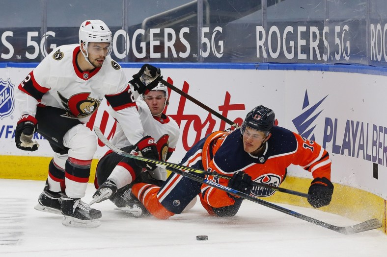 Mar 8, 2021; Edmonton, Alberta, CAN; Edmonton Oilers forward Jesse Puljujarvi (13) and Ottawa Senators defensemen Artem Zub (2) battle for a loose puck during the first period at Rogers Place. Mandatory Credit: Perry Nelson-USA TODAY Sports