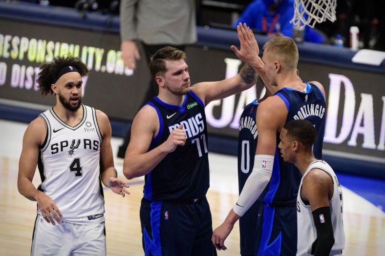 Mar 10, 2021; Dallas, Texas, USA; Dallas Mavericks guard Luka Doncic (77) and center Kristaps Porzingis (6) celebrate as San Antonio Spurs guard Derrick White (4) looks on during the second half at the American Airlines Center. Mandatory Credit: Jerome Miron-USA TODAY Sports