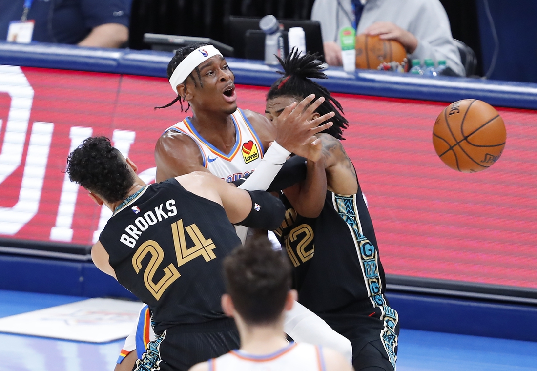 Mar 14, 2021; Oklahoma City, Oklahoma, USA; Oklahoma City Thunder guard Shai Gilgeous-Alexander (C) is fouled while defended by Memphis Grizzlies guard Dillon Brooks (24) and guard Ja Morant (12) during the second half at Chesapeake Energy Arena. Mandatory Credit: Alonzo Adams-USA TODAY Sports