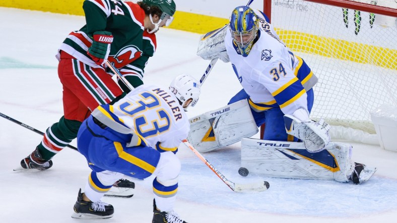 Mar 16, 2021; Newark, New Jersey, USA; Buffalo Sabres goaltender Jonas Johansson (34) makes a save against New Jersey Devils left wing Miles Wood (44) as Buffalo defenseman Colin Miller (33) assists during the second period at Prudential Center. Mandatory Credit: Vincent Carchietta-USA TODAY Sports