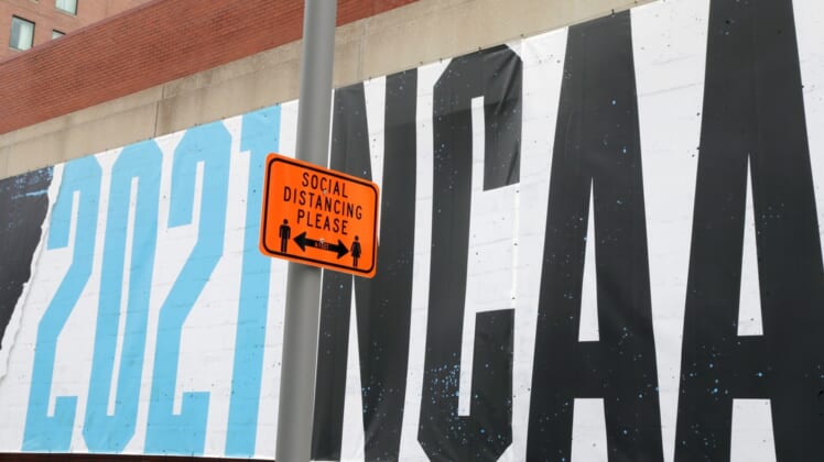 March 17, 2021; Indianapolis, IN, USA; A sign reminding people to social distance is posted in front of a promotional mural in downton Indianapolis as the city prepared to host the 2021 NCAA Division I basketball tournament on Wednesday, March 17, 2021. Indianapolis is hosting the entire tournament this year from the First Four to the National Championship game due to the coronavirus pandemic. Mandatory Credit:Barbara J. Perenic/Columbus Dispatch-USA TODAY Sports