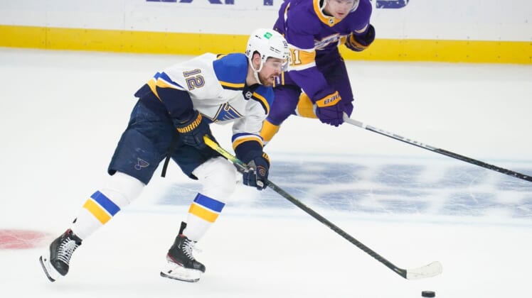 Mar 17, 2021; Los Angeles, California, USA; St. Louis Blues left wing Zach Sanford (12) moves the puck down the ice as Los Angeles Kings left wing Carl Grundstrom (91) gives chase during the first period at Staples Center. Mandatory Credit: Robert Hanashiro-USA TODAY Sports