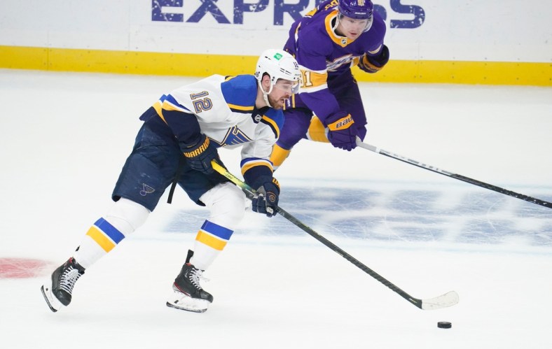 Mar 17, 2021; Los Angeles, California, USA; St. Louis Blues left wing Zach Sanford (12) moves the puck down the ice as Los Angeles Kings left wing Carl Grundstrom (91) gives chase during the first period at Staples Center. Mandatory Credit: Robert Hanashiro-USA TODAY Sports
