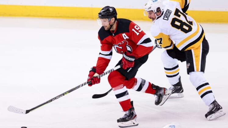 Mar 18, 2021; Newark, New Jersey, USA; New Jersey Devils center Travis Zajac (19) skates with the puck as Pittsburgh Penguins center Sidney Crosby (87) chases during the first period at Prudential Center. Mandatory Credit: Vincent Carchietta-USA TODAY Sports
