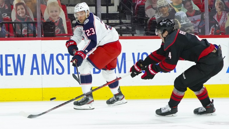 Mar 18, 2021; Raleigh, North Carolina, USA;  Columbus Blue Jackets Stefan Matteau (23) shoots against Carolina Hurricanes defenseman Haydn Fleury (4) during the first period at PNC Arena. Mandatory Credit: James Guillory-USA TODAY Sports