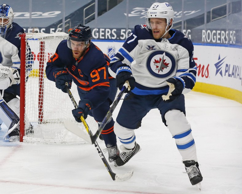 Mar 18, 2021; Edmonton, Alberta, CAN; Edmonton Oilers forward Connor McDavid (97) and Winnipeg Jets forward Nikolaj Ehlers (27) battle for a loose puck during the third period at Rogers Place. Mandatory Credit: Perry Nelson-USA TODAY Sports