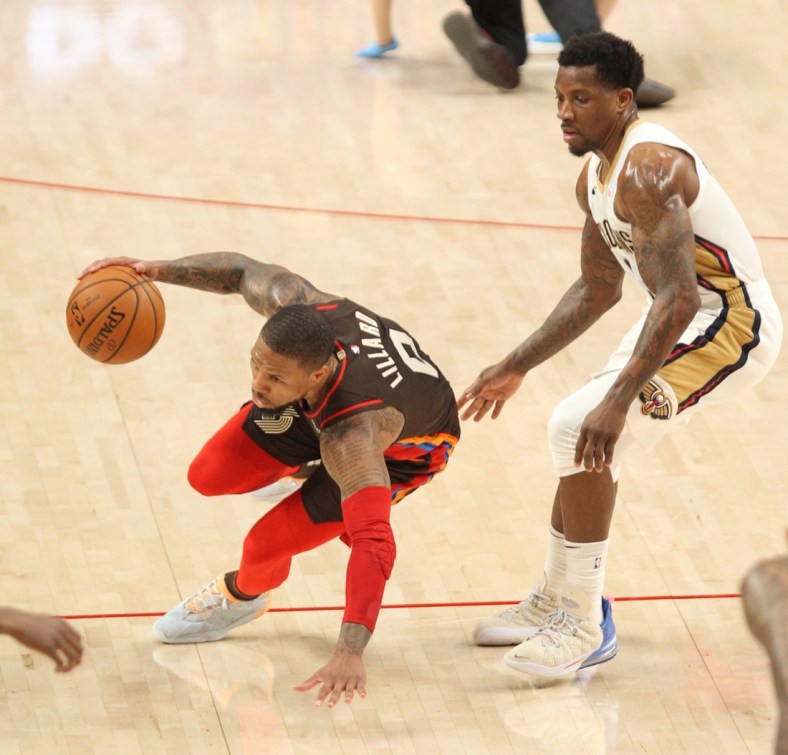 Mar 18, 2021; Portland, Oregon, USA;  Portland Trail Blazers guard Damian Lillard (0) falls after being fouled by New Orleans Pelicans guard Eric Bledsoe (5) in the second half at Moda Center. Mandatory Credit: Jaime Valdez-USA TODAY Sports