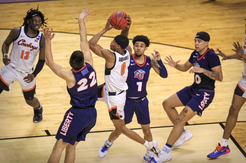 Mar 19, 2021; Indianapolis, IN, USA; Oklahoma State Cowboys guard Avery Anderson III (0) drives to the basket past Liberty Flames forward Kyle Rode (22) and guard Chris Parker (1) and guard Elijah Cuffee (10) during the first round of the 2021 NCAA Tournament at Indiana Farmers Coliseum.  Mandatory Credit: Aaron Doster-USA TODAY Sports