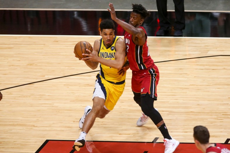 Mar 19, 2021; Miami, Florida, USA; Indiana Pacers guard Malcolm Brogdon (7) controls the basketball around Miami Heat forward Jimmy Butler (22) during the first quarter at American Airlines Arena. Mandatory Credit: Sam Navarro-USA TODAY Sports
