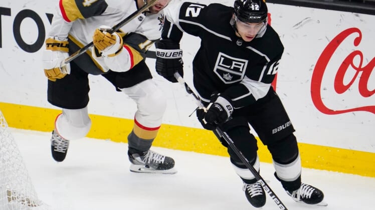 Mar 19, 2021; Los Angeles, California, USA; Los Angeles Kings center Trevor Moore (12) moves the puck away from Vegas Golden Knights defenseman Nicolas Hague (14) during the second period at Staples Center. Mandatory Credit: Robert Hanashiro-USA TODAY Sports