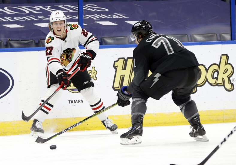 Mar 20, 2021; Tampa, Florida, USA; Chicago Blackhawks defenseman Adam Boqvist (27) passes the puck as Tampa Bay Lightning center Anthony Cirelli (71) defends during the second period at Amalie Arena. Mandatory Credit: Kim Klement-USA TODAY Sports
