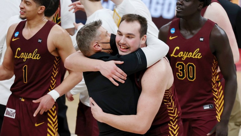 Mar 21, 2021; Indianapolis, Indiana, USA; Loyola Ramblers center Cameron Krutwig (25) hugs head coach Porter Moser after their win over the Illinois Fighting Illini in the second round of the 2021 NCAA Tournament at Bankers Life Fieldhouse. The Loyola Ramblers won 71-58. Mandatory Credit: Trevor Ruszkowski-USA TODAY Sports