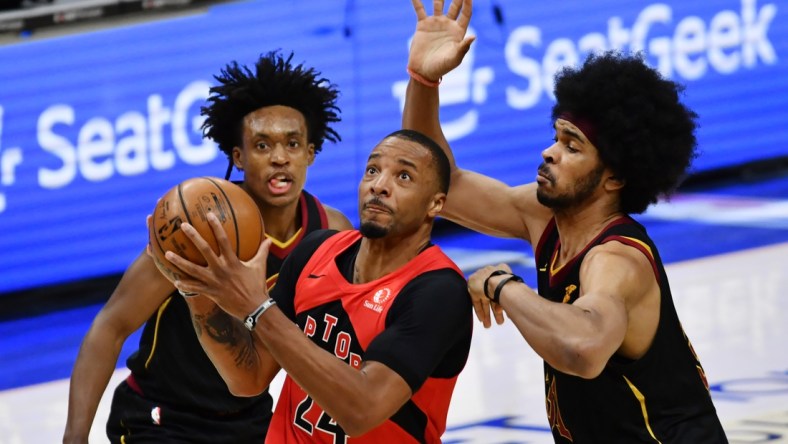 Mar 21, 2021; Cleveland, Ohio, USA; Toronto Raptors forward Norman Powell (24) drives to the basket between Cleveland Cavaliers guard Collin Sexton (2) and center Jarrett Allen (31) during the third quarter at Rocket Mortgage FieldHouse. Mandatory Credit: Ken Blaze-USA TODAY Sports