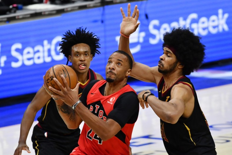Mar 21, 2021; Cleveland, Ohio, USA; Toronto Raptors forward Norman Powell (24) drives to the basket between Cleveland Cavaliers guard Collin Sexton (2) and center Jarrett Allen (31) during the third quarter at Rocket Mortgage FieldHouse. Mandatory Credit: Ken Blaze-USA TODAY Sports