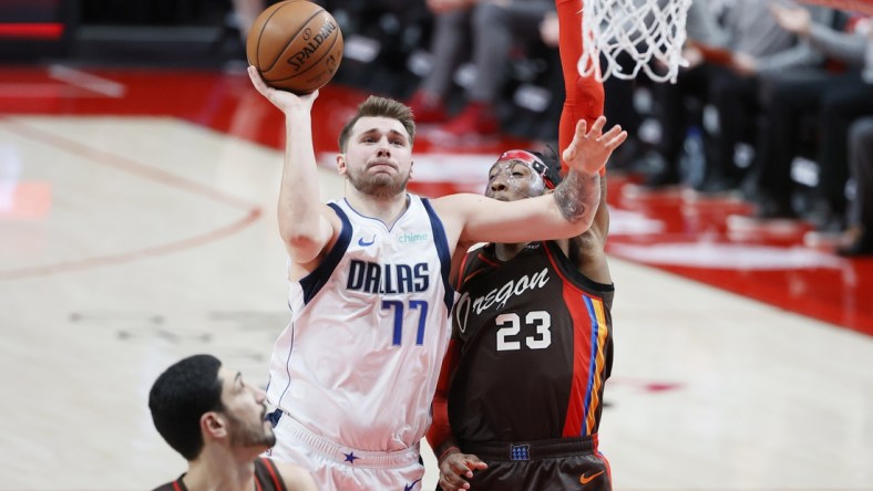 Mar 21, 2021; Portland, Oregon, USA;  Dallas Mavericks point guard Luka Doncic (77) is called for traveling as he shoots against Portland Trail Blazers power forward Robert Covington (23) during the first half at Moda Center. Mandatory Credit: Soobum Im-USA TODAY Sports