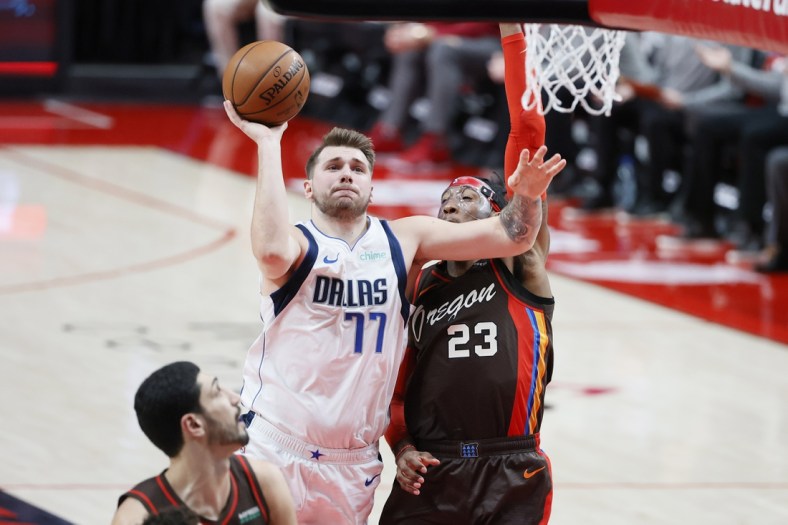 Mar 21, 2021; Portland, Oregon, USA;  Dallas Mavericks point guard Luka Doncic (77) is called for traveling as he shoots against Portland Trail Blazers power forward Robert Covington (23) during the first half at Moda Center. Mandatory Credit: Soobum Im-USA TODAY Sports