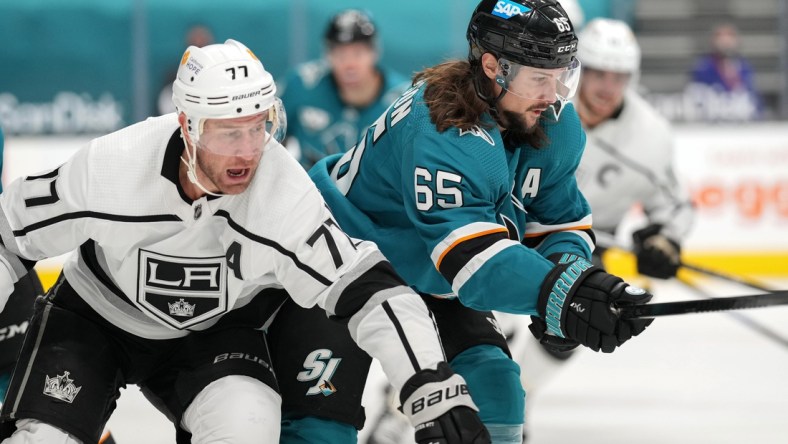 Mar 22, 2021; San Jose, California, USA;  Los Angeles Kings center Jeff Carter (77) and San Jose Sharks defenseman Erik Karlsson (65) chase after the puck during the first period at SAP Center at San Jose. Mandatory Credit: Stan Szeto-USA TODAY Sports