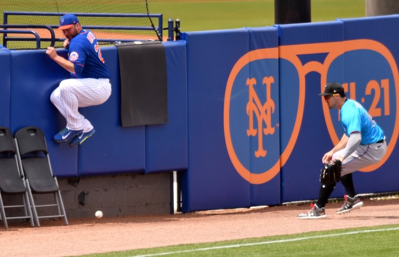 Mar 23, 2021; Port St. Lucie, Florida, USA; New York Mets pitcher Tommy Hunter (L) jumps out of the path of a fair ball as Miami Marlins left fielder Adam Duvall (14) tries to gather the ball in the third inning during a spring training game at Clover Park. Mandatory Credit: Jim Rassol-USA TODAY Sports