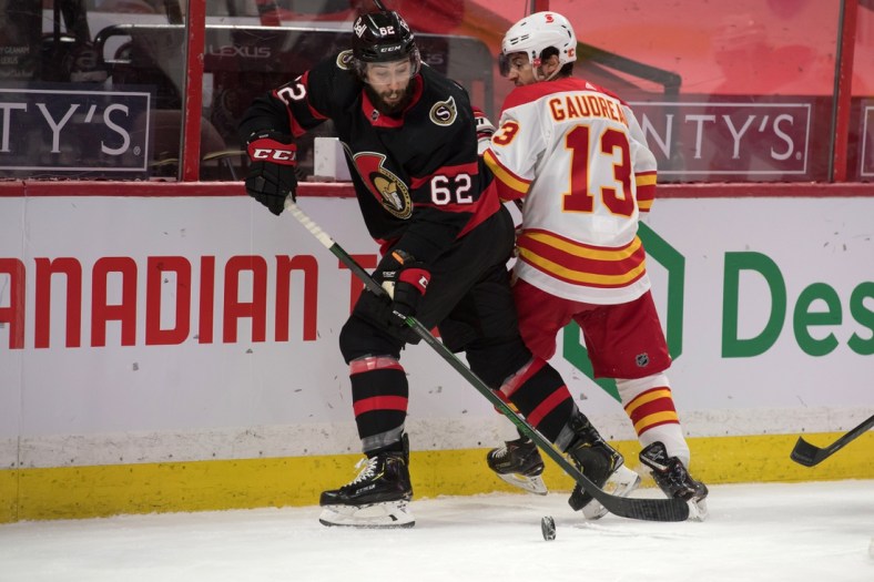 Mar 24, 2021; Ottawa, Ontario, CAN; Ottawa Senators center Clark Bishop (62) steals the puck from Calgary Flames left wing Johnny Gaudreau (13) during the first period at the Canadian Tire Centre. Mandatory Credit: Marc DesRosiers-USA TODAY Sports