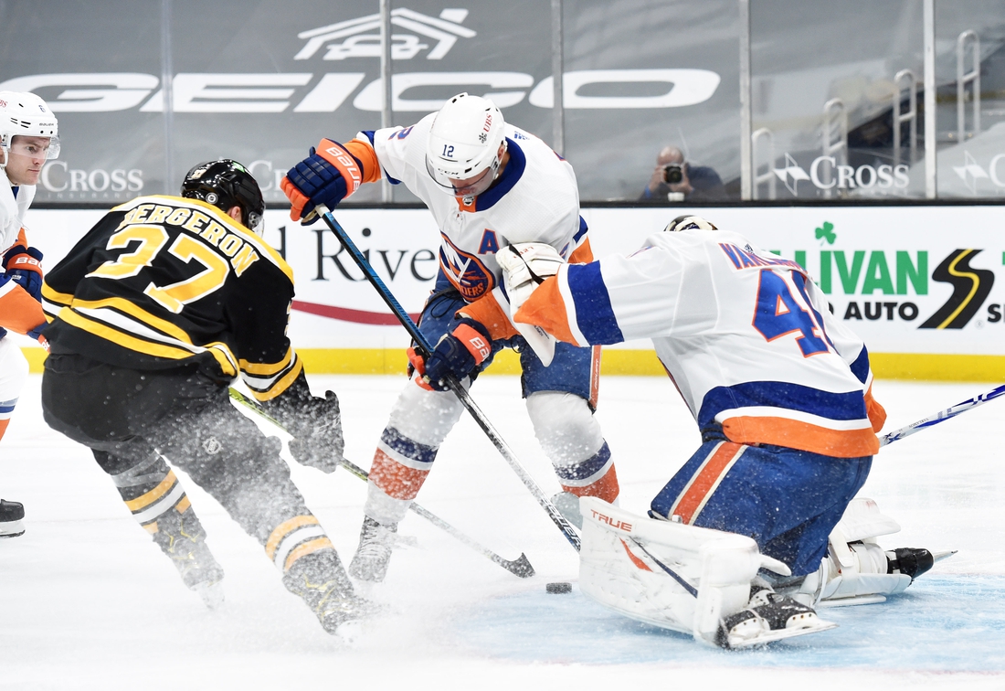 Mar 25, 2021; Boston, Massachusetts, USA; Boston Bruins center Patrice Bergeron (37) and New York Islanders center Josh Bailey (12) battle for a loos puck in front of goaltender Semyon Varlamov (40) during the first period at TD Garden. Mandatory Credit: Bob DeChiara-USA TODAY Sports