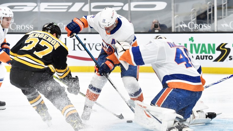 Mar 25, 2021; Boston, Massachusetts, USA; Boston Bruins center Patrice Bergeron (37) and New York Islanders center Josh Bailey (12) battle for a loos puck in front of goaltender Semyon Varlamov (40) during the first period at TD Garden. Mandatory Credit: Bob DeChiara-USA TODAY Sports