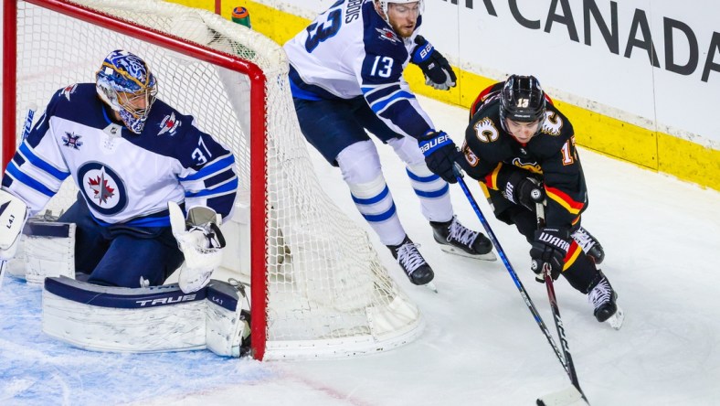 Mar 26, 2021; Calgary, Alberta, CAN; Winnipeg Jets goaltender Connor Hellebuyck (37) guards his net as Calgary Flames left wing Johnny Gaudreau (13) and Winnipeg Jets center Pierre-Luc Dubois (13) battle for the puck during the second period at Scotiabank Saddledome. Mandatory Credit: Sergei Belski-USA TODAY Sports