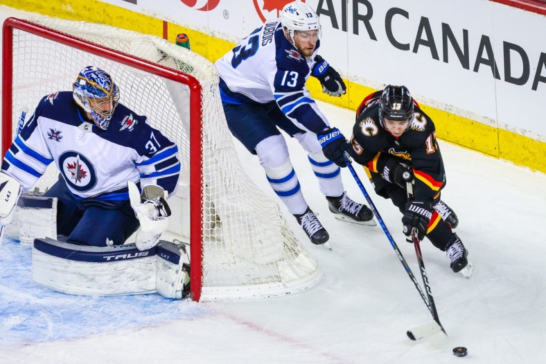 Mar 26, 2021; Calgary, Alberta, CAN; Winnipeg Jets goaltender Connor Hellebuyck (37) guards his net as Calgary Flames left wing Johnny Gaudreau (13) and Winnipeg Jets center Pierre-Luc Dubois (13) battle for the puck during the second period at Scotiabank Saddledome. Mandatory Credit: Sergei Belski-USA TODAY Sports