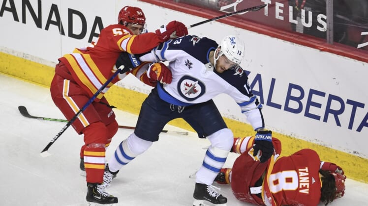 Mar 29, 2021; Calgary, Alberta, CAN; Calgary Flames defenseman Noah Hanifin (55) reacts to a hit on defenseman Christopher Tanev (8) from Winnipeg Jets forward Pierre-Luc Dubois (13) during the first period at Scotiabank Saddledome. Mandatory Credit: Candice Ward-USA TODAY Sports