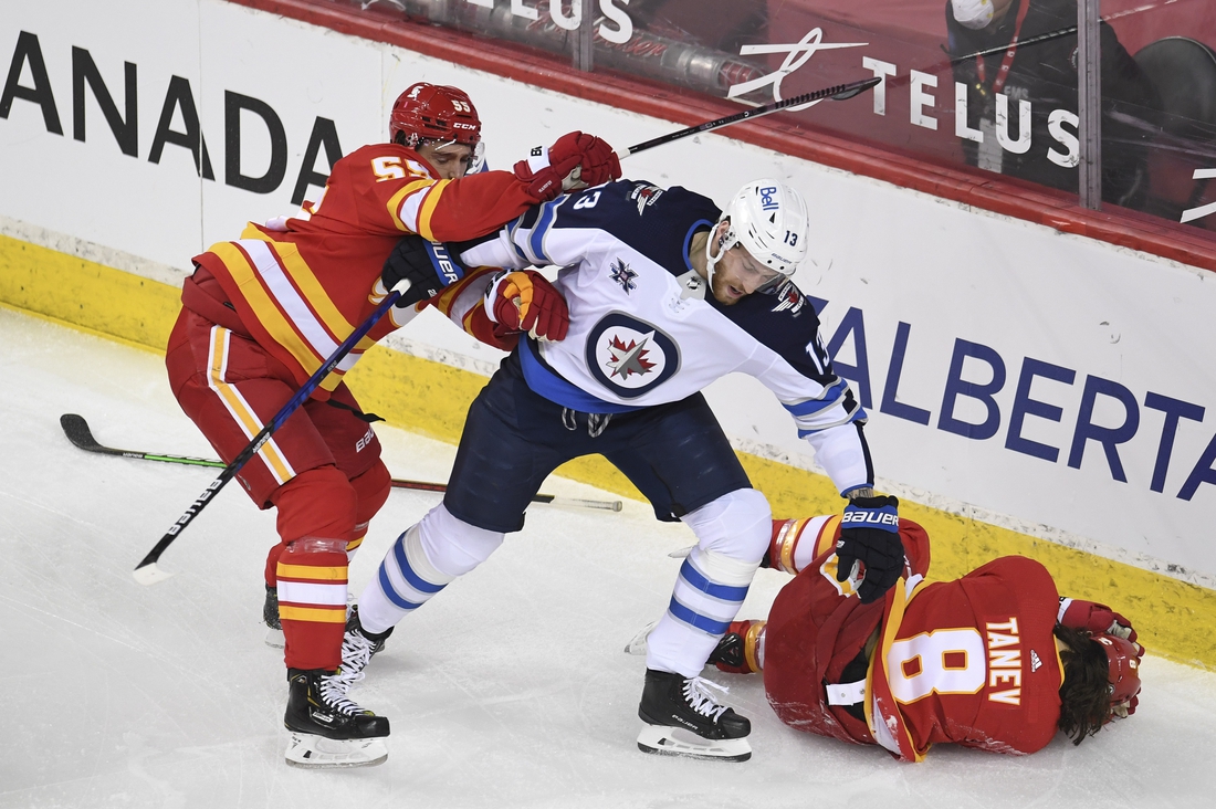 Mar 29, 2021; Calgary, Alberta, CAN; Calgary Flames defenseman Noah Hanifin (55) reacts to a hit on defenseman Christopher Tanev (8) from Winnipeg Jets forward Pierre-Luc Dubois (13) during the first period at Scotiabank Saddledome. Mandatory Credit: Candice Ward-USA TODAY Sports