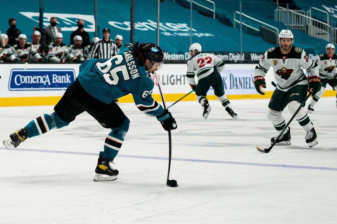 Mar 29, 2021; San Jose, California, USA; San Jose Sharks defenseman Erik Karlsson (65) passes the puck against Minnesota Wild right wing Ryan Hartman (38) during the first period at SAP Center at San Jose. Mandatory Credit: Neville E. Guard-USA TODAY Sports