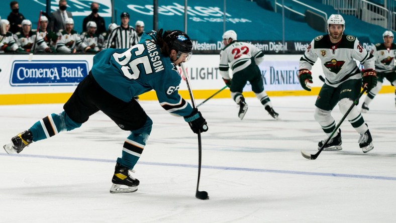 Mar 29, 2021; San Jose, California, USA; San Jose Sharks defenseman Erik Karlsson (65) passes the puck against Minnesota Wild right wing Ryan Hartman (38) during the first period at SAP Center at San Jose. Mandatory Credit: Neville E. Guard-USA TODAY Sports