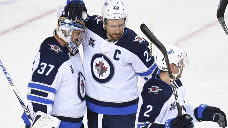 Mar 29, 2021; Calgary, Alberta, CAN; Winnipeg Jets goalie Connor Hellebuyck (37) celebrates with forward Blake Wheeler (26) after a victory over the Calgary Flames at Scotiabank Saddledome. Mandatory Credit: Candice Ward-USA TODAY Sports