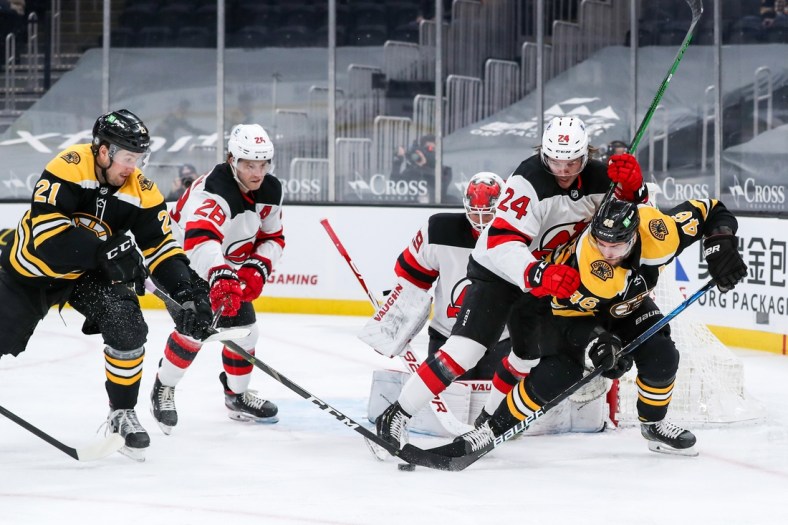 Mar 30, 2021; Boston, Massachusetts, USA; Boston Bruins left wing Nick Ritchie (21) and center David Krejci (46) and New Jersey Devils defenseman Ty Smith (24) battle for the puck during the first period at TD Garden. Mandatory Credit: Paul Rutherford-USA TODAY Sports
