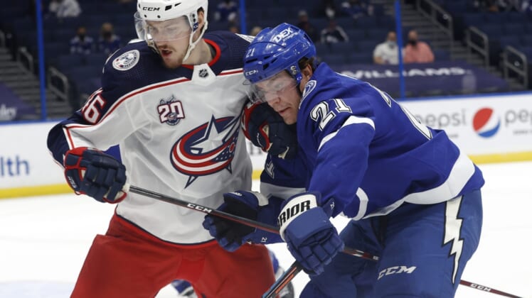 Mar 30, 2021; Tampa, Florida, USA; Columbus Blue Jackets defenseman Dean Kukan (46) and Tampa Bay Lightning center Brayden Point (21) skate with the puck during the first period at Amalie Arena. Mandatory Credit: Kim Klement-USA TODAY Sports