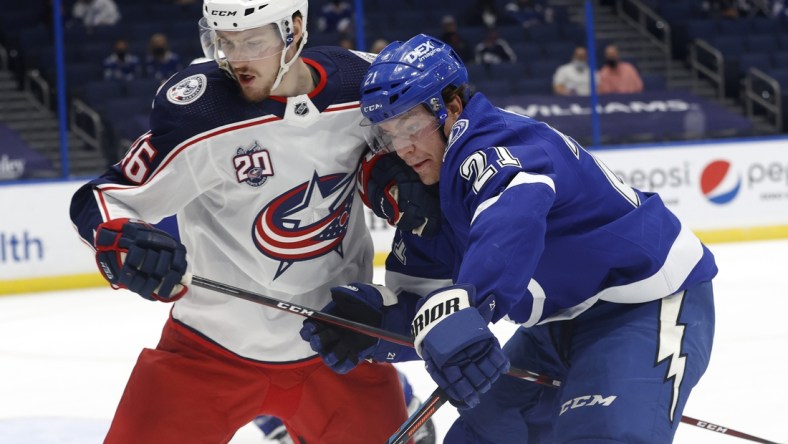 Mar 30, 2021; Tampa, Florida, USA; Columbus Blue Jackets defenseman Dean Kukan (46) and Tampa Bay Lightning center Brayden Point (21) skate with the puck during the first period at Amalie Arena. Mandatory Credit: Kim Klement-USA TODAY Sports