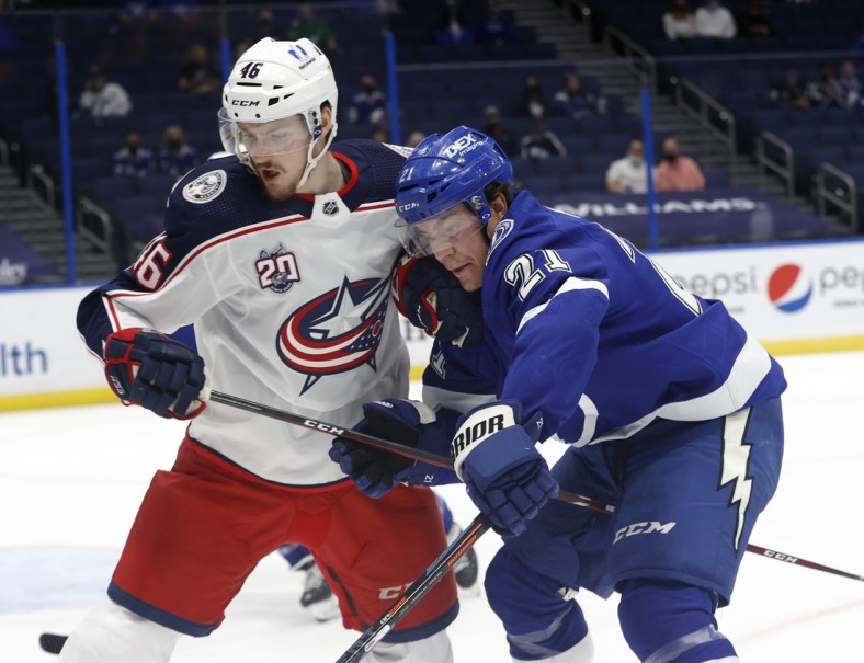 Mar 30, 2021; Tampa, Florida, USA; Columbus Blue Jackets defenseman Dean Kukan (46) and Tampa Bay Lightning center Brayden Point (21) skate with the puck during the first period at Amalie Arena. Mandatory Credit: Kim Klement-USA TODAY Sports