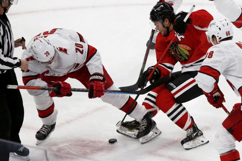 Mar 30, 2021; Chicago, Illinois, USA; Carolina Hurricanes center Sebastian Aho (20) battles for the puck with Chicago Blackhawks Alex DeBrincat (12) during the first period at United Center. Mandatory Credit: Eileen T. Meslar-USA TODAY Sports