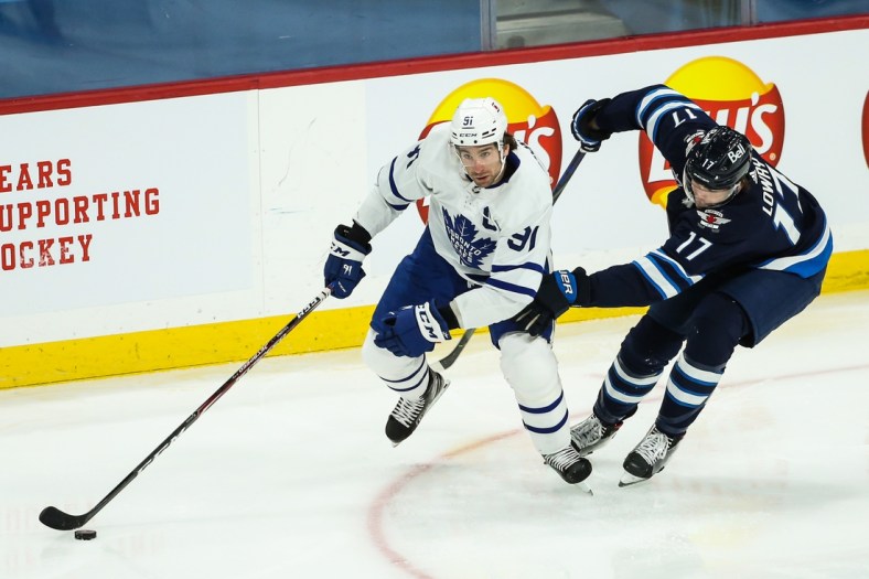 Mar 31, 2021; Winnipeg, Manitoba, CAN; Toronto Maple Leafs forward John Taveres (91) skates with the puck while defended by Winnipeg Jets forward Adam Lowry (17) during the first period at Bell MTS Place. Mandatory Credit: Terrence Lee-USA TODAY Sports