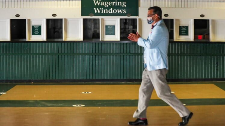 Sep 4, 2020; Louisville, Kentucky, USA;  A man rubs his hands with sanitizer as he walks past empty Wagering Windows at Churchill Downs on the 2020 Oaks Day Friday morning. No fans are allowed for Oaks nor the Kentucky Derby due to Covid-19: only horse owners, trainers, jockeys and family. Mandatory Credit: Matt Stone/Louisville Courier-Journal-USA TODAY NETWORK