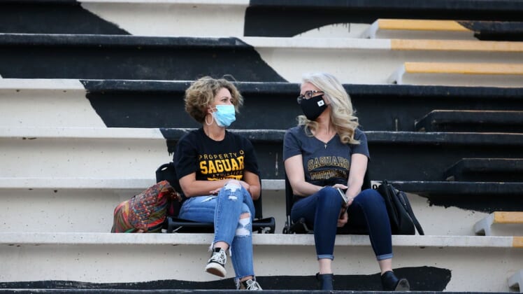 High school football fans wear masks during a national televised game at Saguaro High School. Mandatory Credit: Rob Schumacher/The Arizona Republic via USA TODAY NETWORK
