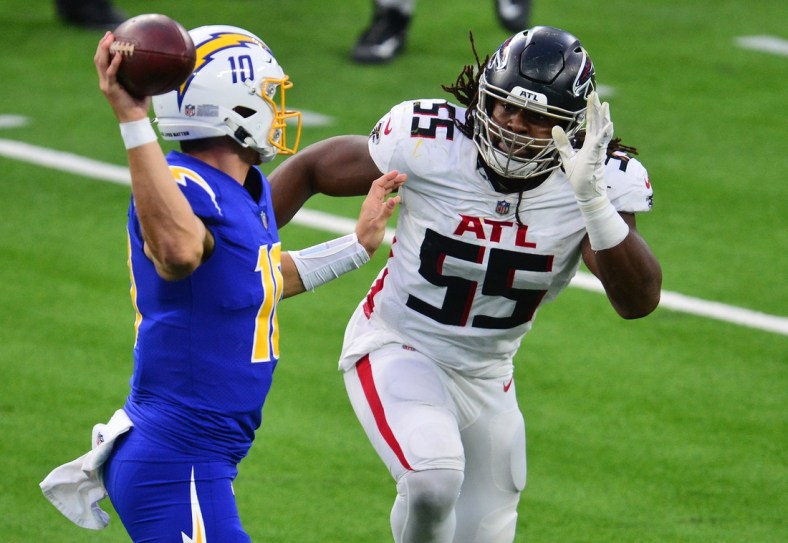 Dec 13, 2020; Inglewood, California, USA; Los Angeles Chargers quarterback Justin Herbert (10) throws under pressure against Atlanta Falcons defensive end Steven Means (55) during the second half at SoFi Stadium. Mandatory Credit: Gary A. Vasquez-USA TODAY Sports