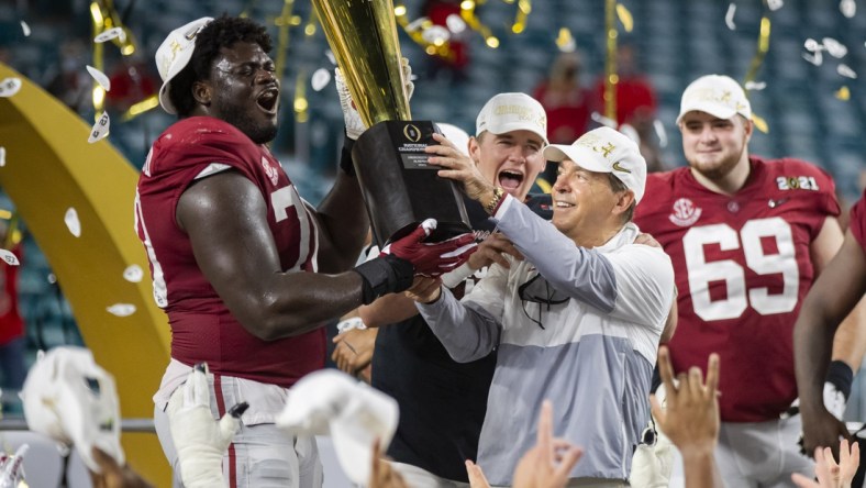 Jan 11, 2021; Miami Gardens, Florida, USA; Alabama Crimson Tide head coach Nick Saban and offensive lineman Alex Leatherwood (70) celebrates with the CFP National Championship trophy after beating the Ohio State Buckeyes in the 2021 College Football Playoff National Championship Game. Mandatory Credit: Mark J. Rebilas-USA TODAY Sports