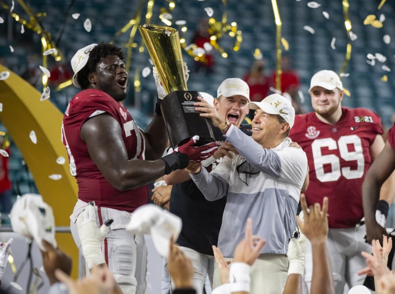 Jan 11, 2021; Miami Gardens, Florida, USA; Alabama Crimson Tide head coach Nick Saban and offensive lineman Alex Leatherwood (70) celebrates with the CFP National Championship trophy after beating the Ohio State Buckeyes in the 2021 College Football Playoff National Championship Game. Mandatory Credit: Mark J. Rebilas-USA TODAY Sports
