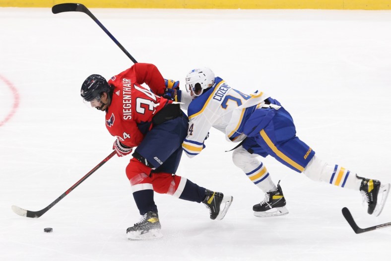 Jan 22, 2021; Washington, District of Columbia, USA; Washington Capitals defenseman Jonas Siegenthaler (34) battles for the puck with Buffalo Sabres center Dylan Cozens (24) in the second period at Capital One Arena. Mandatory Credit: Geoff Burke-USA TODAY Sports