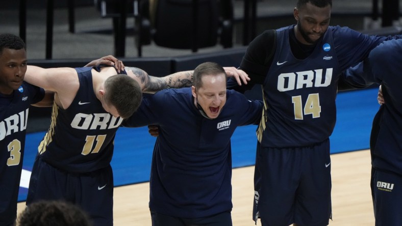 Mar 19, 2021; West Lafayette, Indiana, USA; Oral Roberts Golden Eagles guard Max Abmas (3) and guard Carlos Jurgens (11) and head coach Paul Mills and forward DeShang Weaver (14) huddle after an overtime victory over the Ohio State Buckeyes in the first round of the 2021 NCAA Tournament at Mackey Arena. Mandatory Credit: Mike Dinovo-USA TODAY Sports