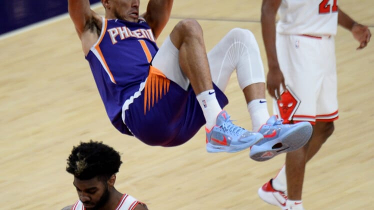 Mar 31, 2021; Phoenix, Arizona, USA; Phoenix Suns guard Devin Booker (1) hangs on the rim after dunking the ball during the first half against the Chicago Bulls at Phoenix Suns Arena. Mandatory Credit: Joe Camporeale-USA TODAY Sports